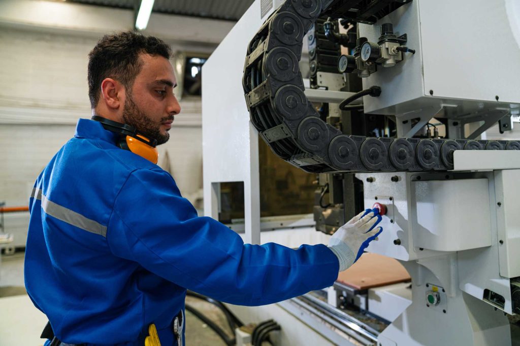 Homem apertando botão de máquina em seu ambiente de trabalho