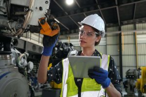 Jovem engenheira verificando peças para montagens com tablet digital