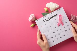 Calendário mostrando o mês de outubro com um laço e fundo rosa
