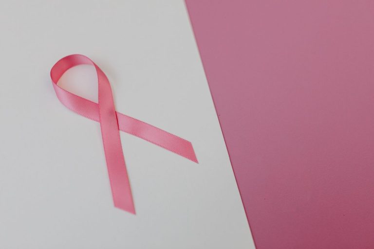 Pink ribbon on a pink background symbolizing breast cancer awareness and support.