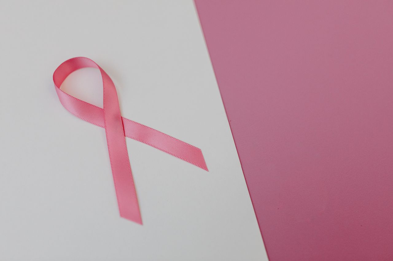 Pink ribbon on a pink background symbolizing breast cancer awareness and support.